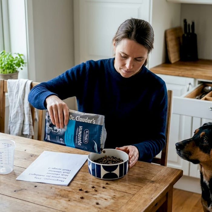 Eieren måler opp og deler hundens mat hjemme for å sikre riktig mengde.